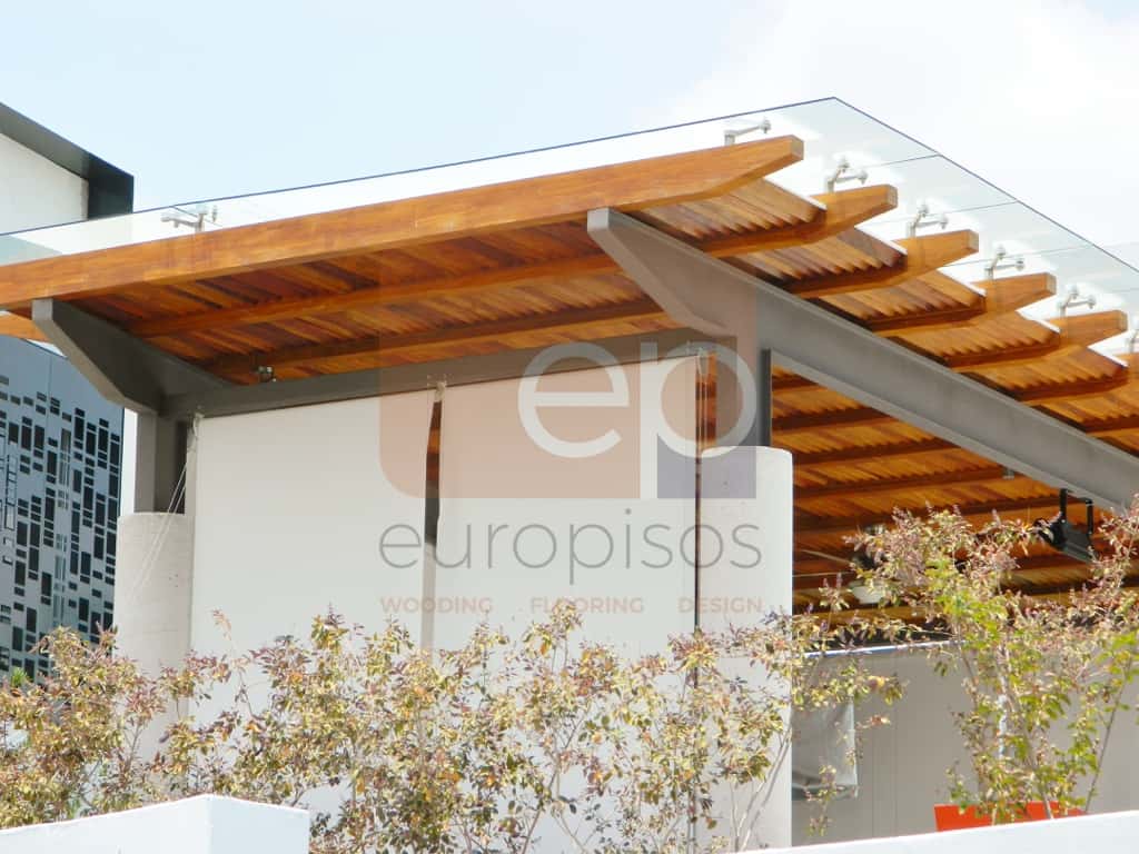 Detalle de pérgola de madera con acabado profesional instalada en una terraza con jardín